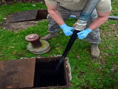 Worker with gloves lowering suction hose into open septic tank — Si View Septic Pumping in North Bend